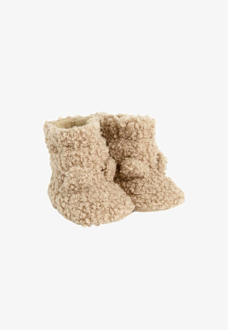 Botitas de bebé beige y suaves, con un diseño texturizado y rizado. Punta redondeada y un forro interior suave, con un detalle decorativo de pom-pom.