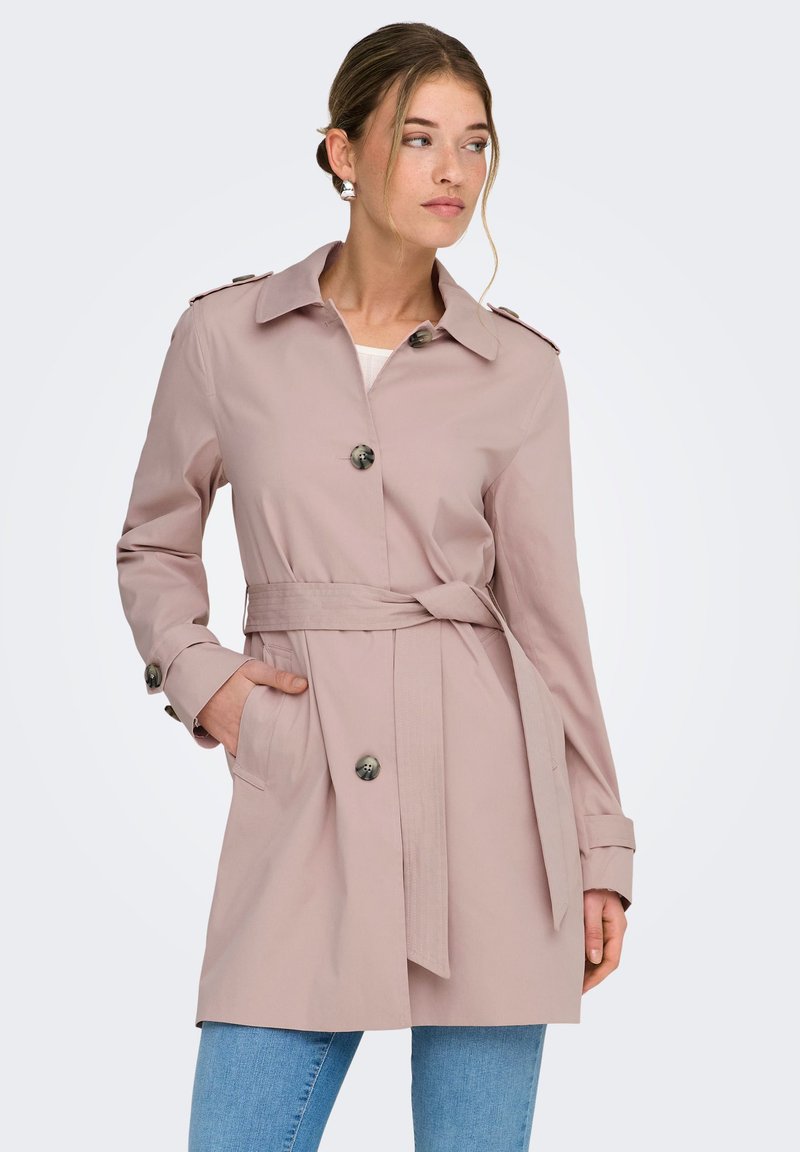 Trench-coat rose clair en tissu lisse, doté d'une ceinture à la taille, de grands boutons et de poches latérales, avec un col classique et des épaulettes.