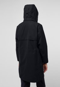 Giacca nera impermeabile con cappuccio, caratterizzata da un design di lunghezza intermedia, una ventilazione posteriore e una texture liscia. Costruzione semplice e dettagli minimi.
