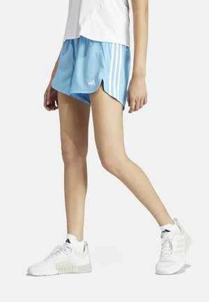 Pantalones cortos deportivos de color azul claro con rayas horizontales blancas y aberturas en los lados, combinados con zapatillas blancas con detalles grises.