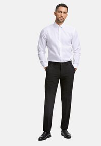 Weißes Hemd mit Knopfverschluss und Kragen, kombiniert mit schwarzen maßgeschneiderten Hosen und schwarzen Lederschuhen. Glattes Material mit klassischer Passform.