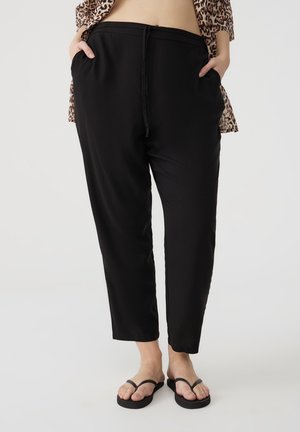 Pantaloni neri in una vestibilità comoda con vita elastica, coulisse regolabile e tasche laterali. Tessuto morbido e design alla caviglia.