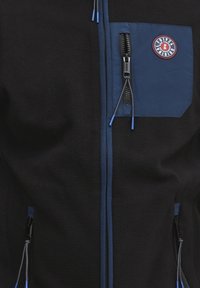 Chaqueta de forro polar negra con acentos azules, que cuenta con un bolsillo en el pecho con cremallera, bolsillos laterales y cremalleras en contraste con tiradores azules.