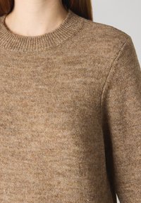 Brown knitted sweater with a ribbed crew neckline, soft texture, and subtle variations in color throughout the fabric.