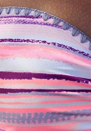 Close-up of fabric with horizontal pastel pink, purple, and white stripes and a gray tasseled edge on a brown surface.