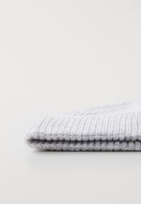 Lichtgrijze, geribbelde gebreide muts met een omgeslagen rand. Zachte textuur en flexibel materiaal ontworpen voor warmte en comfort.