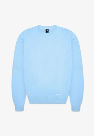 Light blue crewneck sweatshirt made of soft fabric. Features ribbed cuffs and hem, with a small label on the bottom left side.
