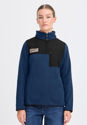 Fleece-pullar i mörkblått med en svart bröstpanel, halvdragkedja och logotypapplikation. Har en framficka med dragkedja och mjuk textur.