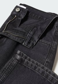 Jeans de mezclilla negra con cremallera y cierre de botón, con costuras en contraste y una superficie suave y texturizada.