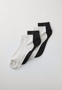 Fire par par bomuldsstrømper i hvid, lys grå og sort. Har en ribbet struktur og subtil branding på ribben.
