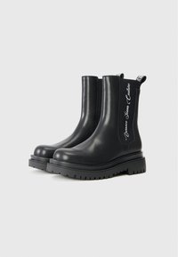 Black ankle boots made of smooth leather with a chunky rubber sole and pull tabs. Features side goring and logo detailing on the shaft.