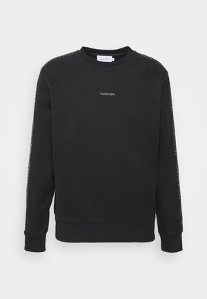 Czarna bluza Calvin Klein z okrągłym dekoltem, długimi rękawami i małym białym logo na środku klatki piersiowej oraz wzdłuż obu rękawów.
