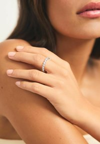 Bague en argent sterling avec des pierres claires serties sur griffes, mettant en valeur un design courbé. Fini lisse avec un aspect poli.