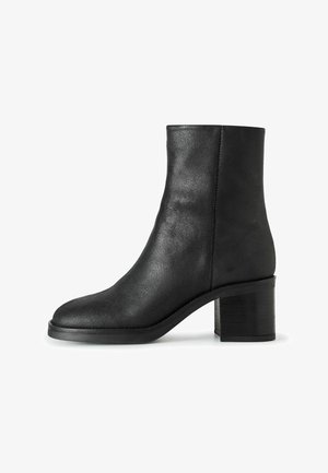Stivale alla caviglia in pelle nera con punta rotonda, tacco a blocco di altezza media, texture liscia e dettagli di cucitura minimi.
