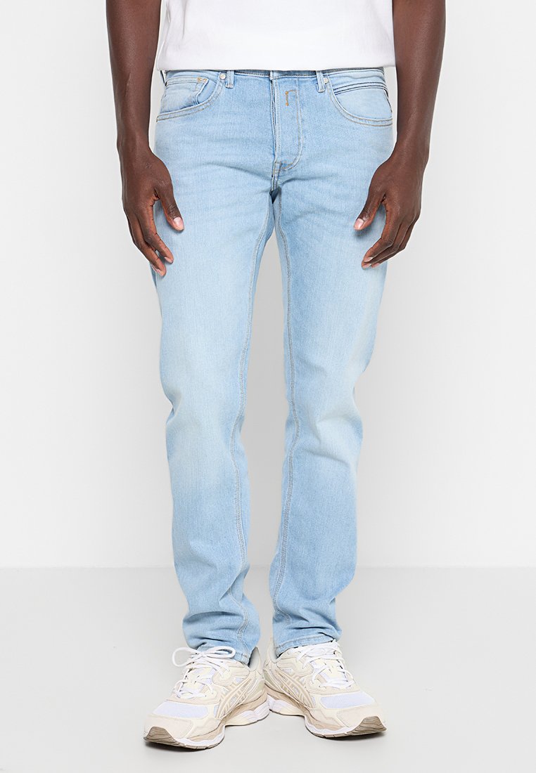 Lichtblauwe spijkerbroek met een slim fit, vijf zakken en vervagingselementen. Draag het met neutraal gekleurde sneakers.