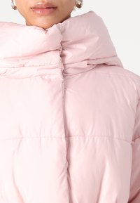 Giacca imbottita rosa chiaro con colletto alto e strutturato, finitura lucida e sottili dettagli di cucitura orizzontale.