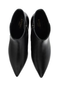 Botas de cuero negras hasta el tobillo con un diseño de punta afilada, que cuentan con cremalleras laterales y una textura suave. En el interior marcadas con "ESTIMA, Milano."