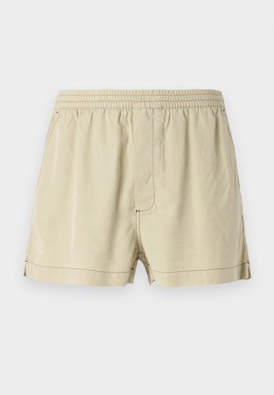 Beige shorts made of lightweight fabric with an elastic waistband, flat front, and side seams. Features subtle texture and no pockets.