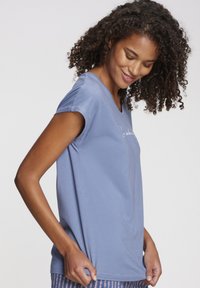 Light blue short-sleeve T-shirt with a V-neck design. Soft fabric with a relaxed fit. Features a simple front print and smooth texture.