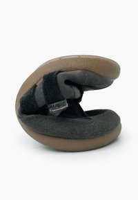 Pantofole flessibili piegate di colore grigio scuro e marrone con cinturino regolabile nero su uno sfondo bianco.