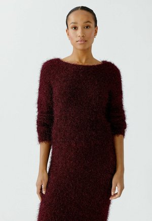 Bordeauxfarbendes Strickkleid mit einer weichen, flauschigen Textur, weitem Ausschnitt und dreiviertellangen Ärmeln, das einen lockeren, entspannten Schnitt aufweist.