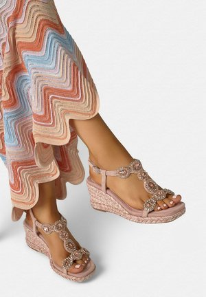 Voeten met roze sleehakken met kralenriempjes, gecombineerd met een meerkleurige golvende gebreide rok in pasteltinten.