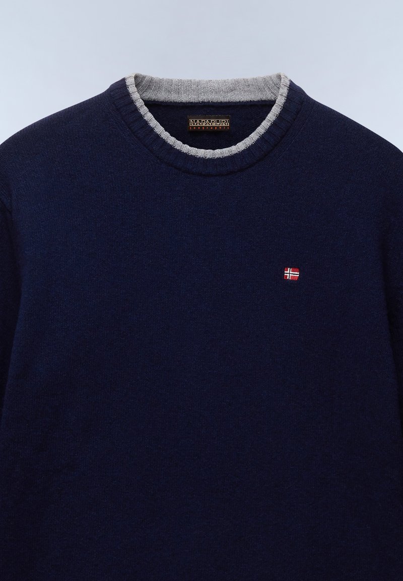 Granatowy sweter z dzianiny z szarym ściągaczem. Posiada małą haftowaną norweską flagę na piersi. Miękka tekstura.