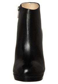 Svart läderankelsko med en slät yta, rund tå och sidodragkedja. Diskret matt textur med låg klack för stabilitet.