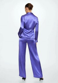 Conjunto de traje de satén morado que incluye una chaqueta ajustada y pantalones de pierna ancha. Textura suave con un sutil brillo, diseñado para un ajuste relajado.
