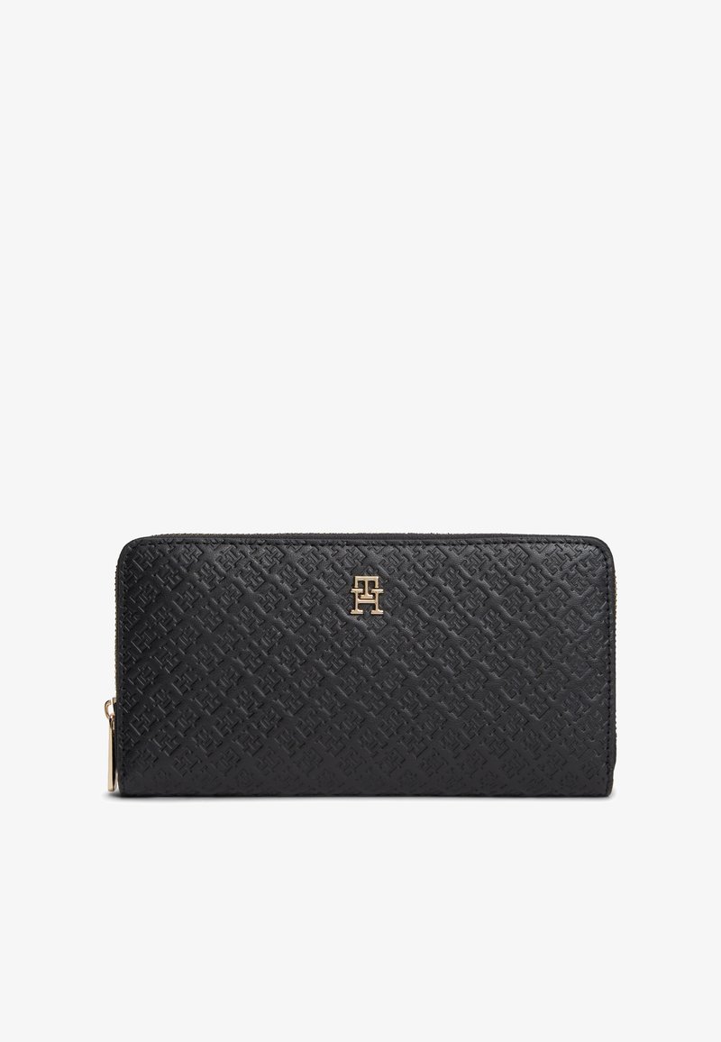 Portefeuille zippé en cuir noir avec motif de logo embossé et petit emblème métallique doré de la marque centré à l'avant.