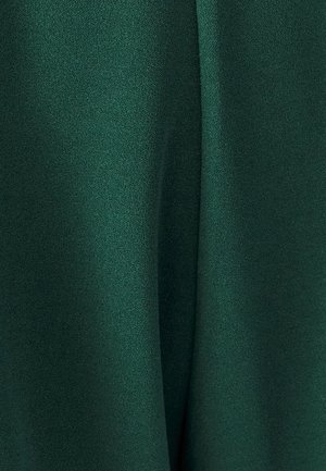 Temno zelena tkanina, gladka tekstura z rahlim sijajem, mehko nabrana z nežnimi pregibi. Brez vidnih vzorcev ali okraskov.