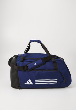 Marineblauwe sporttas met zwarte accenten, gemaakt van duurzaam materiaal. Voorzien van een bovenhandgreep, verstelbare band en een wit gestreept logoontwerp.