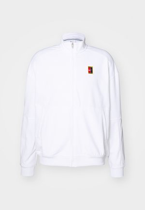 Bela jakna z zadrgo, visokim ovratnikom, rebrastimi manšetami in spodnjim robom ter majhnim pravokotnim večbarvnim logotipom na levi strani prsnega koša.