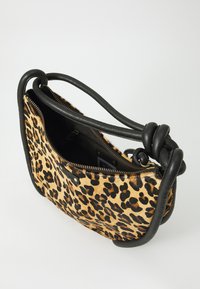 Torba sa leopard uzorkom s teksturiranom krznom, crnim kožnim detaljima i čvorastom ručkom. Ima zatvarač i unutarnju džep.