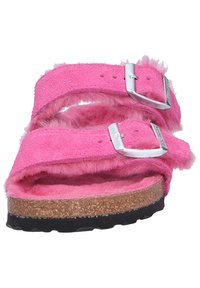 Pink suede sandals with two buckled straps, fuzzy texture, cork footbed, and black rubber outsole. Notable construction details include stitching.