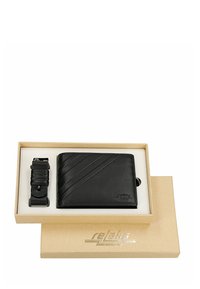 Czarny skórzany portfel i pasujący brelok do kluczy w beżowym pudełku prezentowym z logo "relaks" na pokrywce pudełka.