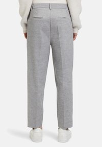 Grijze op maat gemaakte broeken met een gestructureerde stof, rechte pijpen en twee achterzakken. Gecombineerd met witte sneakers voor contrast.