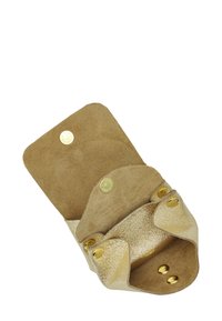 Petit sac en cuir doré ouvert avec boutons-pression et intérieur en daim, conçu pour contenir de petits objets en toute sécurité.
