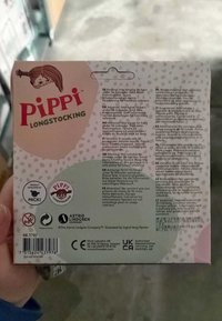 Pippi Langstrumpf Verpackung mit rosa und grünen Farben, Punktenmuster und mehrsprachigen Warnungen zur Altersgerechtigkeit und Sicherheit.