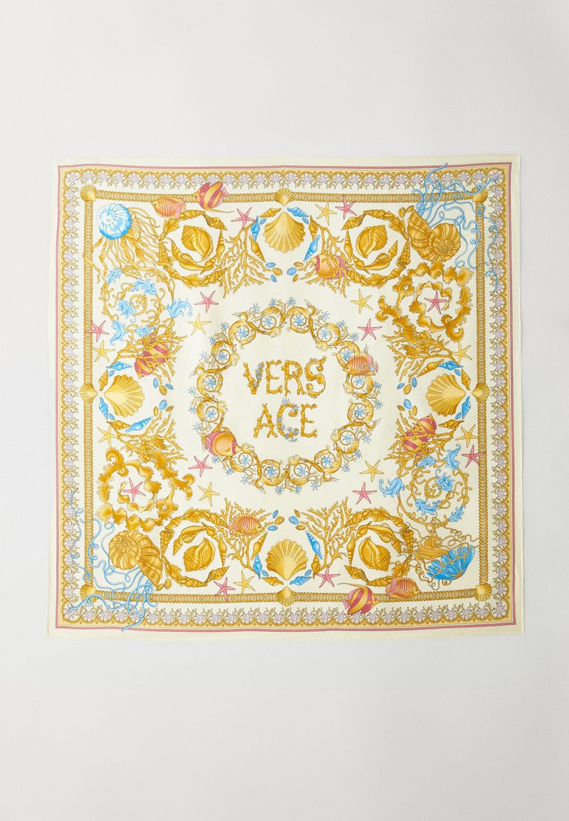 Zīda šalle ar krēms krāsu fonu un zeltainiem, zilām un rozā čūsku un rifu rakstiem. Centrālais dizains ietver "VERSACE" zeltainās burtos.