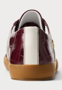 Μπορντώ δερμάτινα αθλητικά παπούτσια με υφή κροκοδείλου, λευκές ρίγες και σόλα από καουτσούκ. Η πίσω όψη δείχνει έναν επενδεδυμένο γιακά.