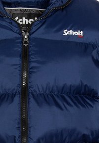 Giacca puffer blu navy con chiusura a zip, caratterizzata da una texture liscia e un logo marcato sul petto sinistro in bianco e rosso.