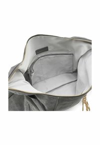 Intérieur d'un sac à main en cuir gris présentant une doublure en tissu lisse, une poche zippée et un compartiment principal avec une fermeture éclair dorée.