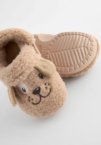 Tan fluffiga tofflor med hundansiktsdesign, med broderade ögon och hängande öron. Gummisula med mönster för bättre grepp.