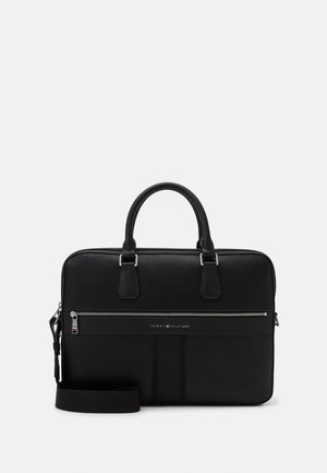 Borsa da lavoro in pelle nera con doppie maniglie, tasca frontale con cerniera, tracolla e logo Tommy Hilfiger su sfondo bianco pulito.