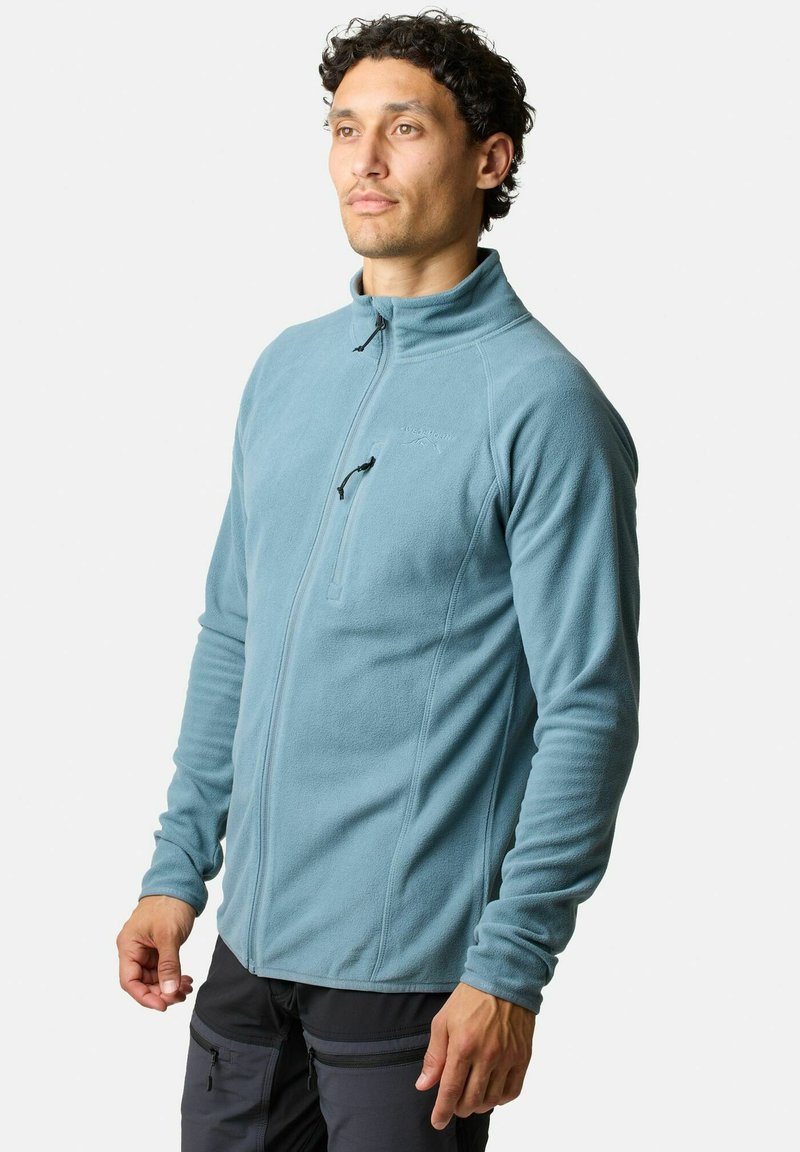 Giacca in fleece di colore azzurro chiaro con design a mezza zip, dotata di colletto alto e cuciture in tono. Il tessuto ha una finitura morbida e testurizzata.