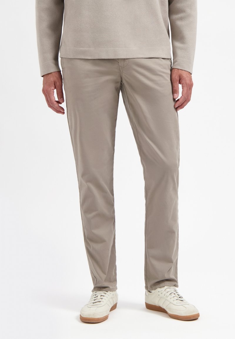 Lichtbeige chino's met een gladde textuur, slim fit en steekzakken. Draagt met witte sneakers met een lichtbruine zool.