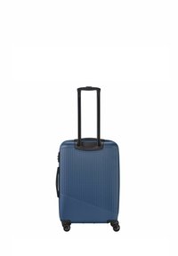 Blauer hartschaliger Koffer mit vertikalen Rillen, ausziehbarem schwarzen Griff, vier Rädern und einem Zickzackmuster auf der Vorderseite.