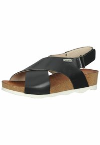 Sandal de tacón negro de piel con tiras entrecruzadas, plantilla de corcho y suela de goma blanca. Correa ajustable para un ajuste seguro.