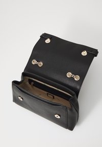 Black leather handbag with gold hardware, a structured design, snap closures, and a lined interior featuring a zip pocket and logo detail.